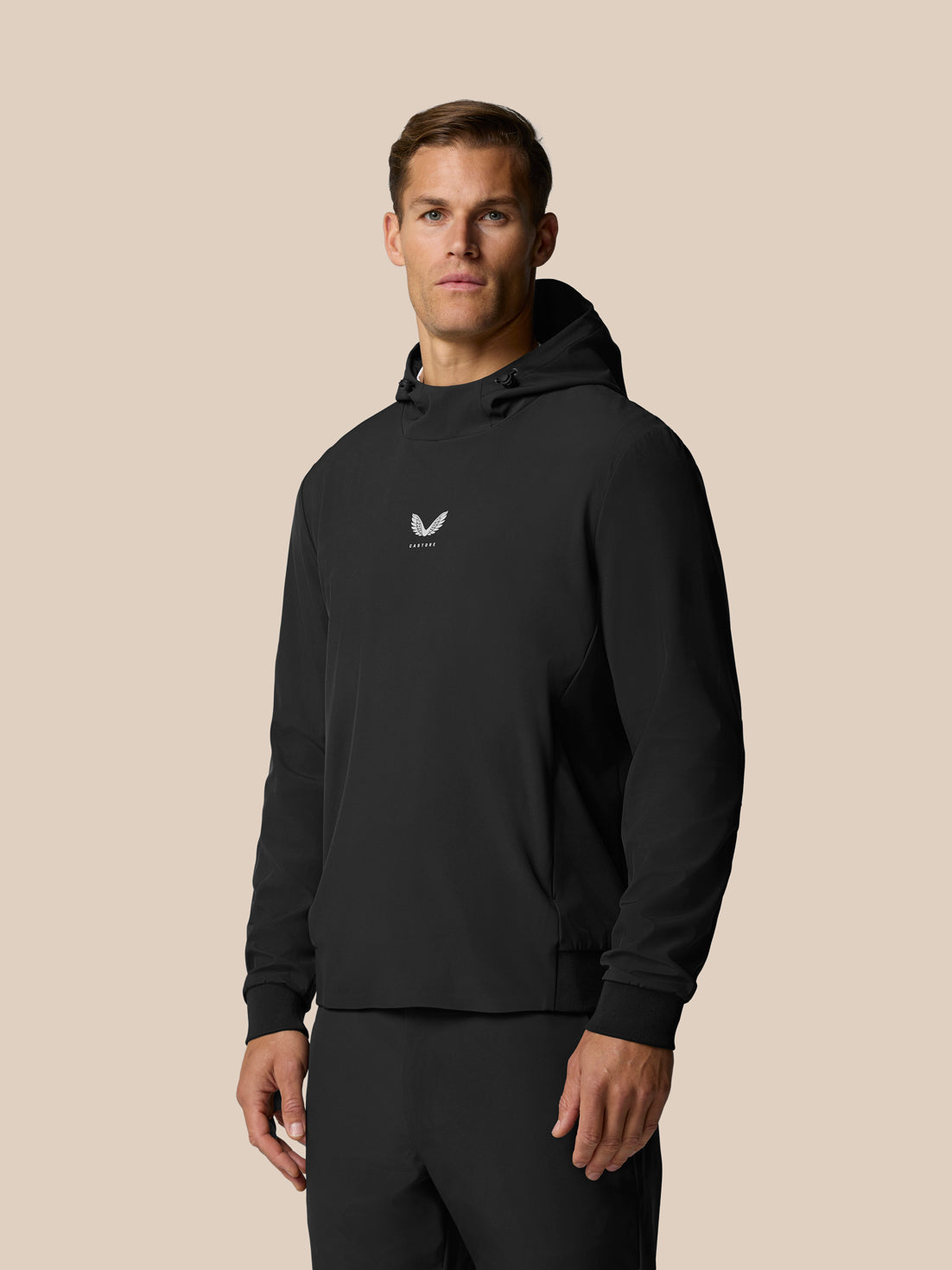 Male model wearing black Castore performance hoodie with drawstring hood and small logo on chest.