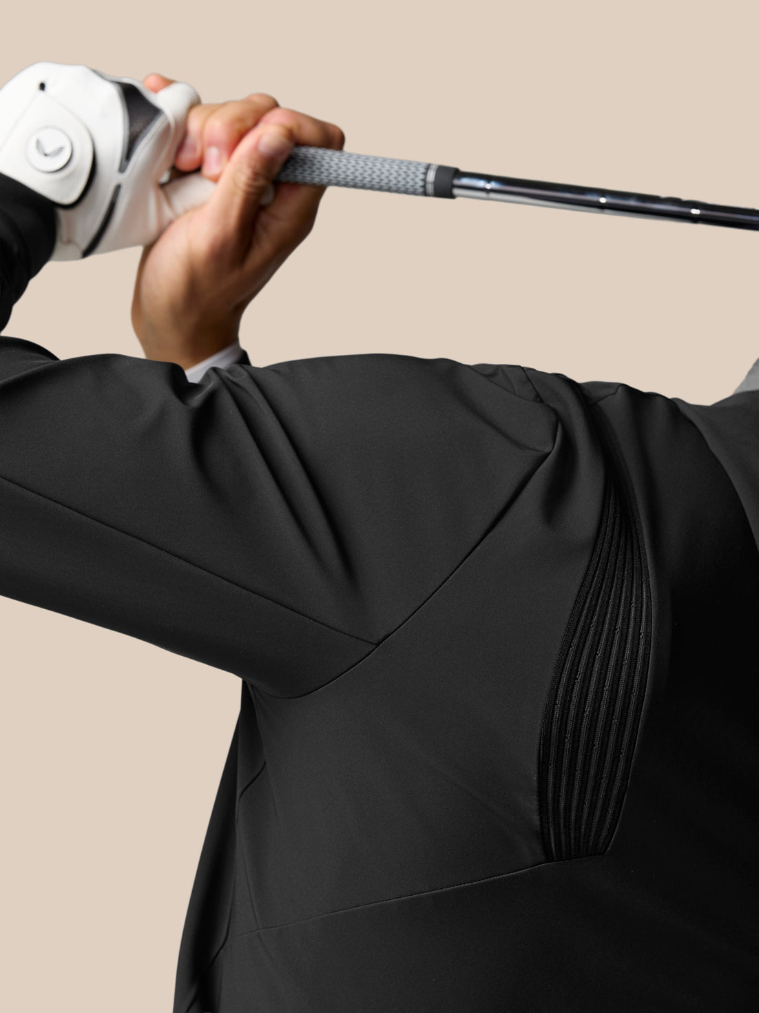 Golfer wearing a black Golf Pinnacle Performance Hoodie grips a golf club with a white glove