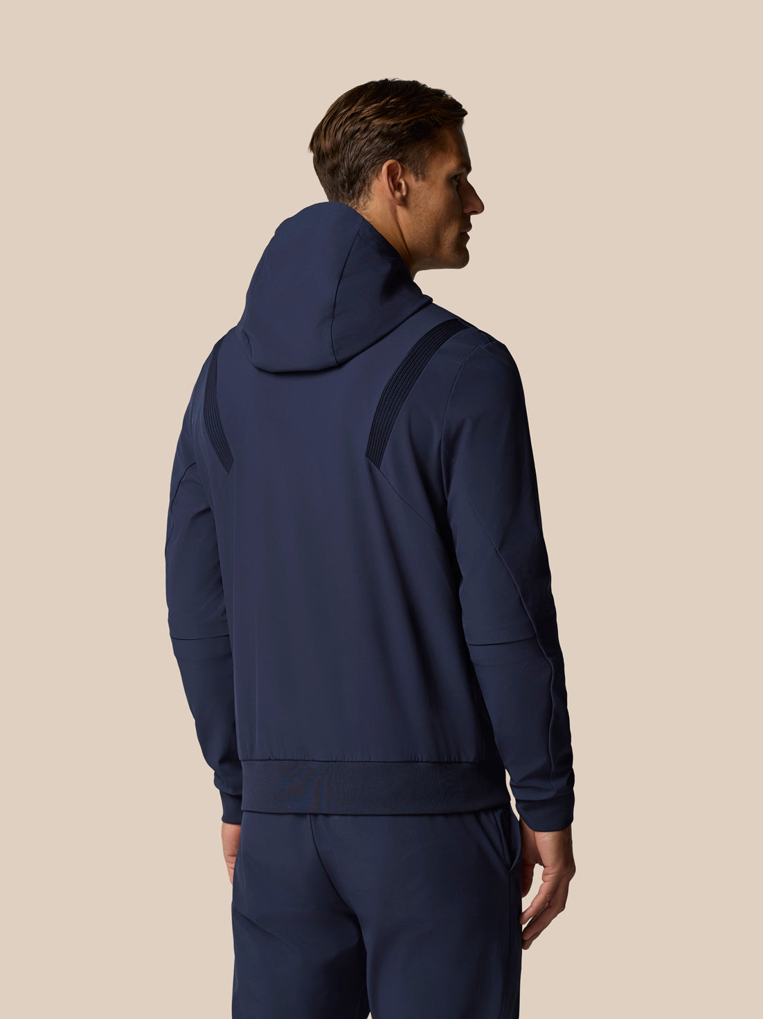 Model wearing the Golf Pinnacle Performance Hoodie in midnight navy seen from the back with hood and shoulder panels