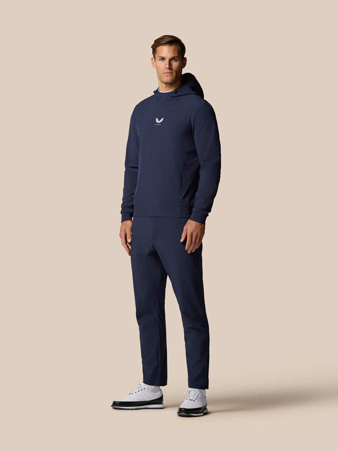 Male model in the Golf Pinnacle Performance Hoodie midnight navy standing in a full length shot showing the chest logo