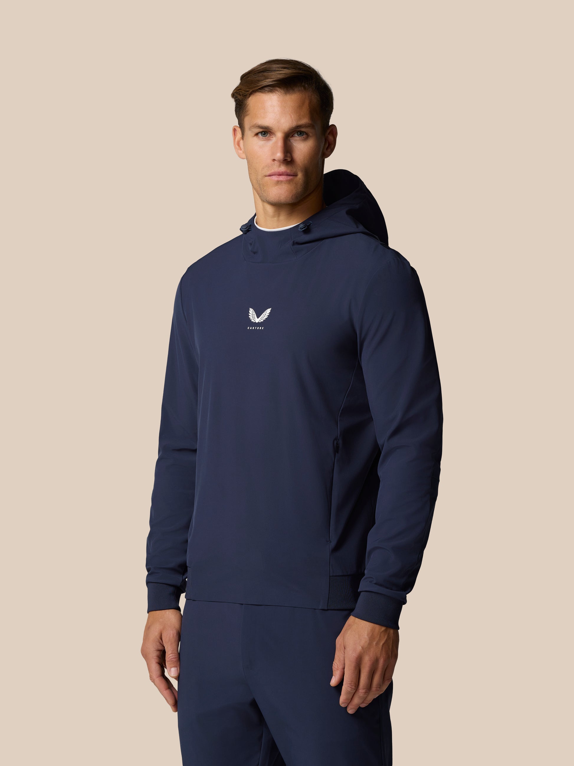 Male model wearing midnight navy Castore Golf Pinnacle Performance Hoodie with center chest logo.