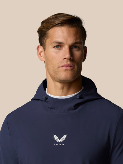 Male model in midnight navy Castore Golf Pinnacle Performance Hoodie with logo on chest and hood visible.