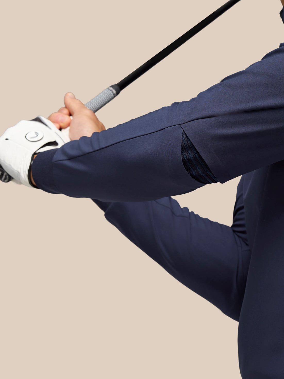 Profile of a golfer in the Midnight Navy Pinnacle Performance Hoodie gripping a golf club mid swing