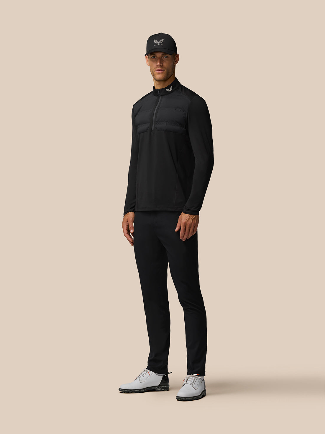 Male model wearing Golf Pinnacle LVS Hybrid 1/2 Zip Top in black alloy, full body shot highlighting the padded chest panel.