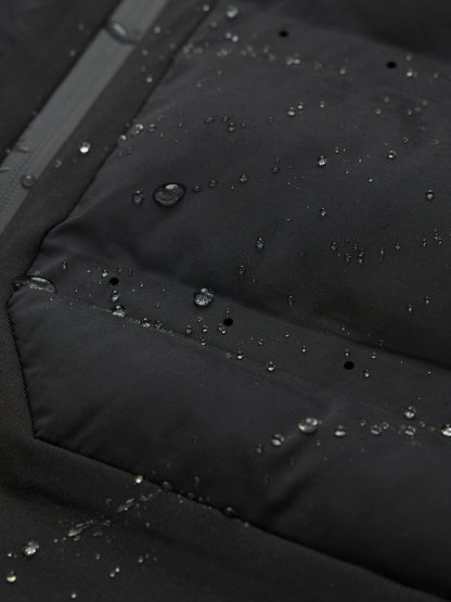 Close up of black LVS fabric with water droplets, zipper, and white wing logo on the collar.
