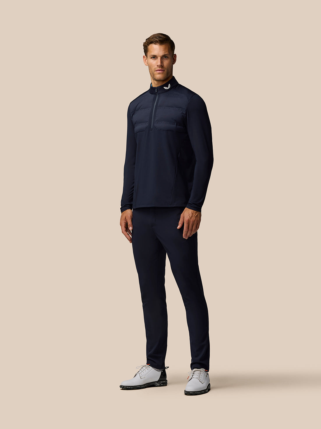 Male model wearing midnight navy Golf Pinnacle LVS Hybrid 1/2 Zip Top with padded chest panel and layered ventilation.