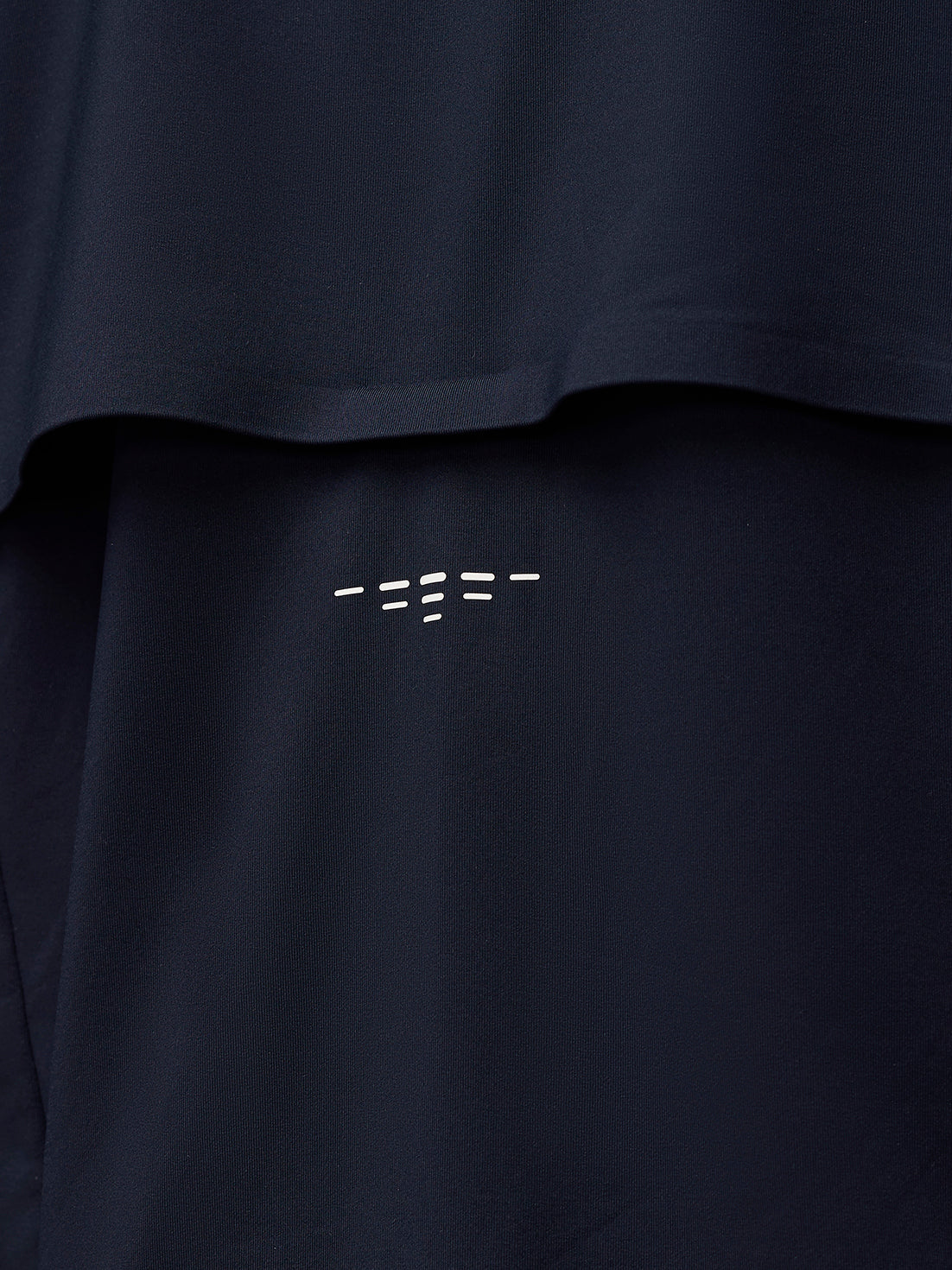 Close-up of navy fabric with PROTEK branding near a seam on the jacket