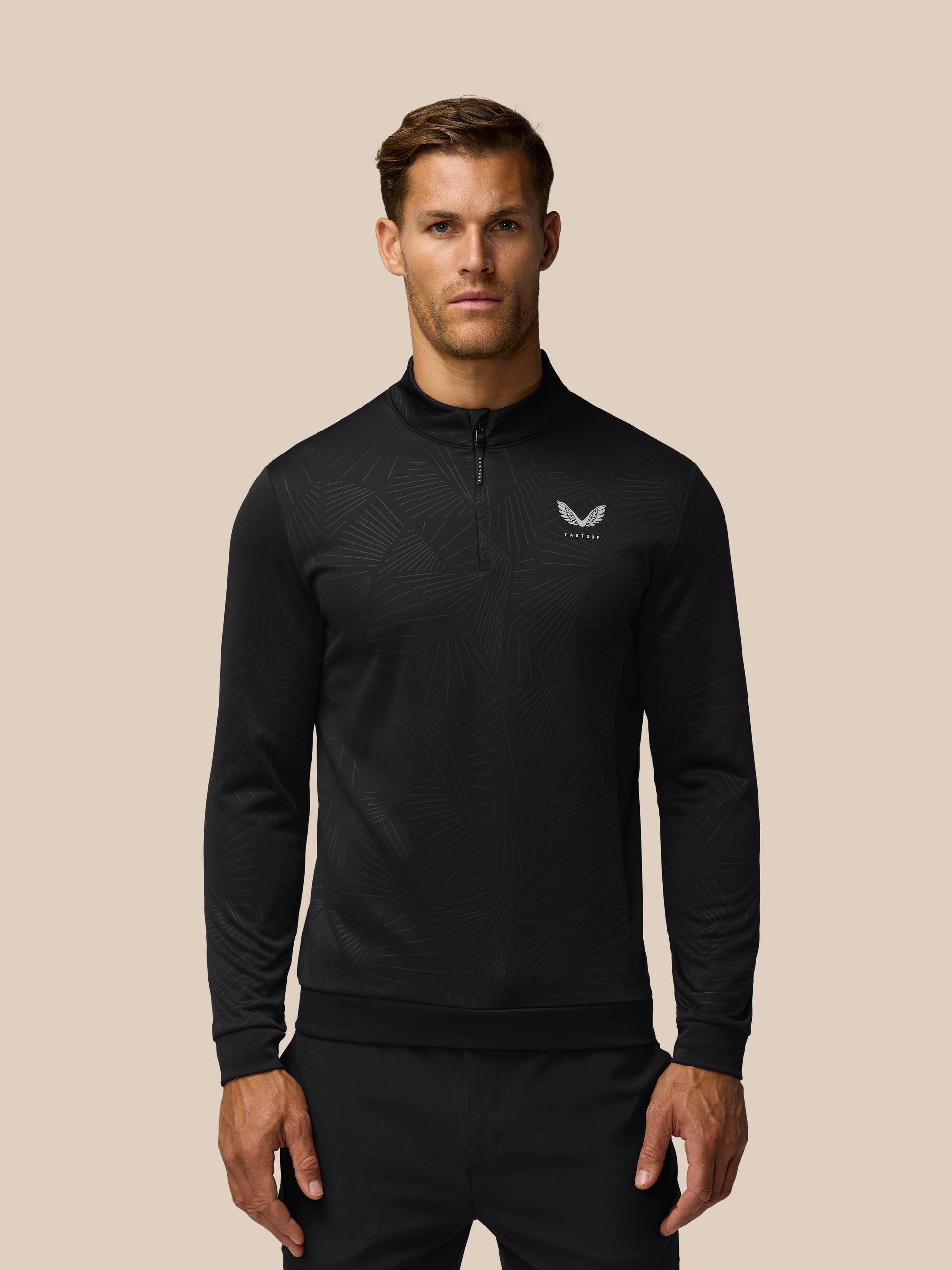 Male model wearing black quarter-zip golf top with an all-over subtle linear print and Castore logo on the left chest.