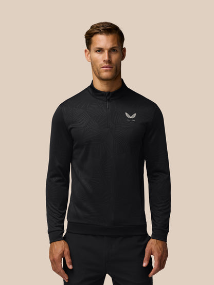 Male model wearing black quarter-zip golf top with an all-over subtle linear print and Castore logo on the left chest.