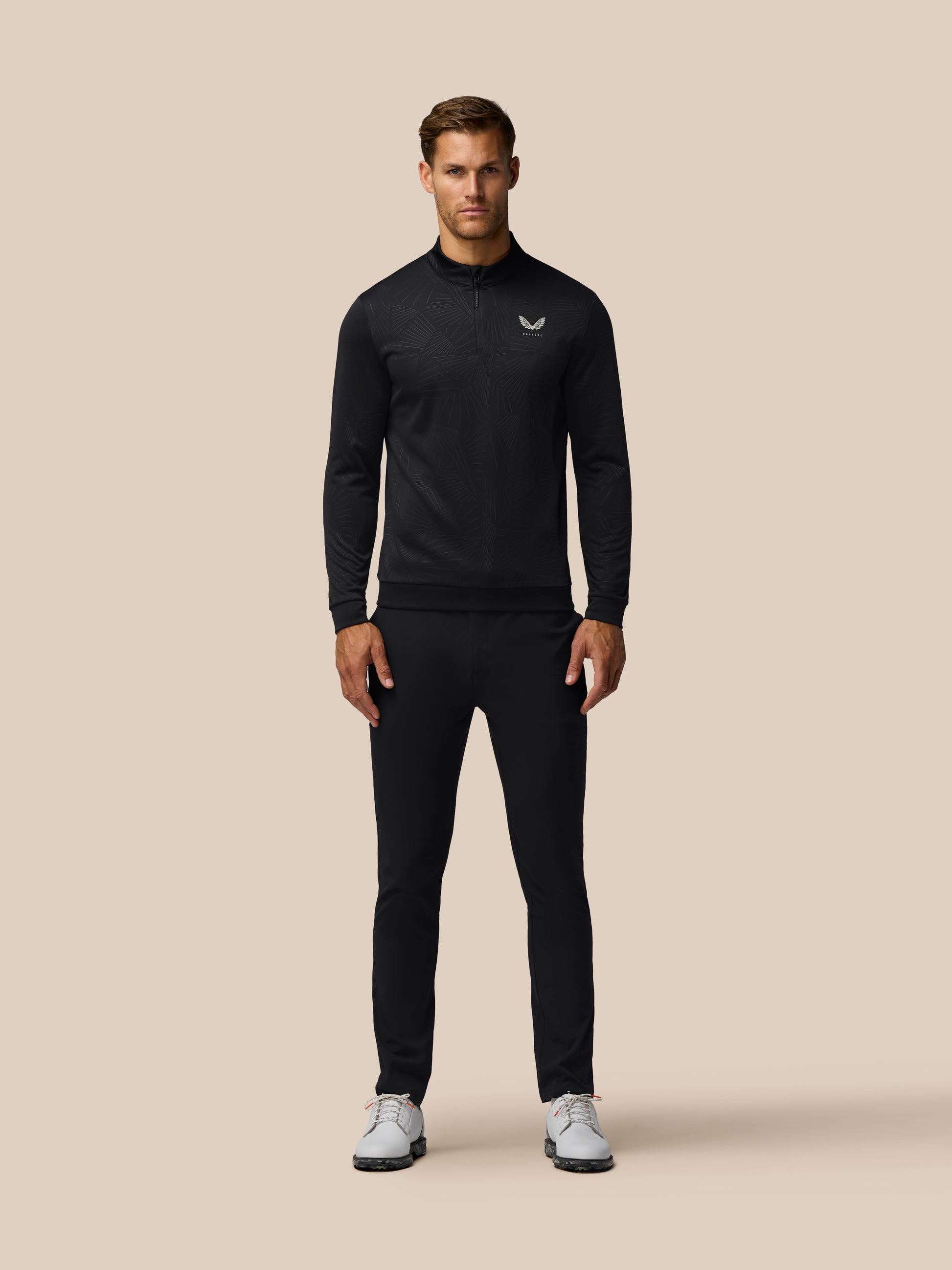 Male model wearing black Golf Club Classic 1/4 Zip Debossed Top with all over print and Castore logo on left chest.