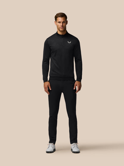 Male model wearing black Golf Club Classic 1/4 Zip Debossed Top with all over print and Castore logo on left chest.
