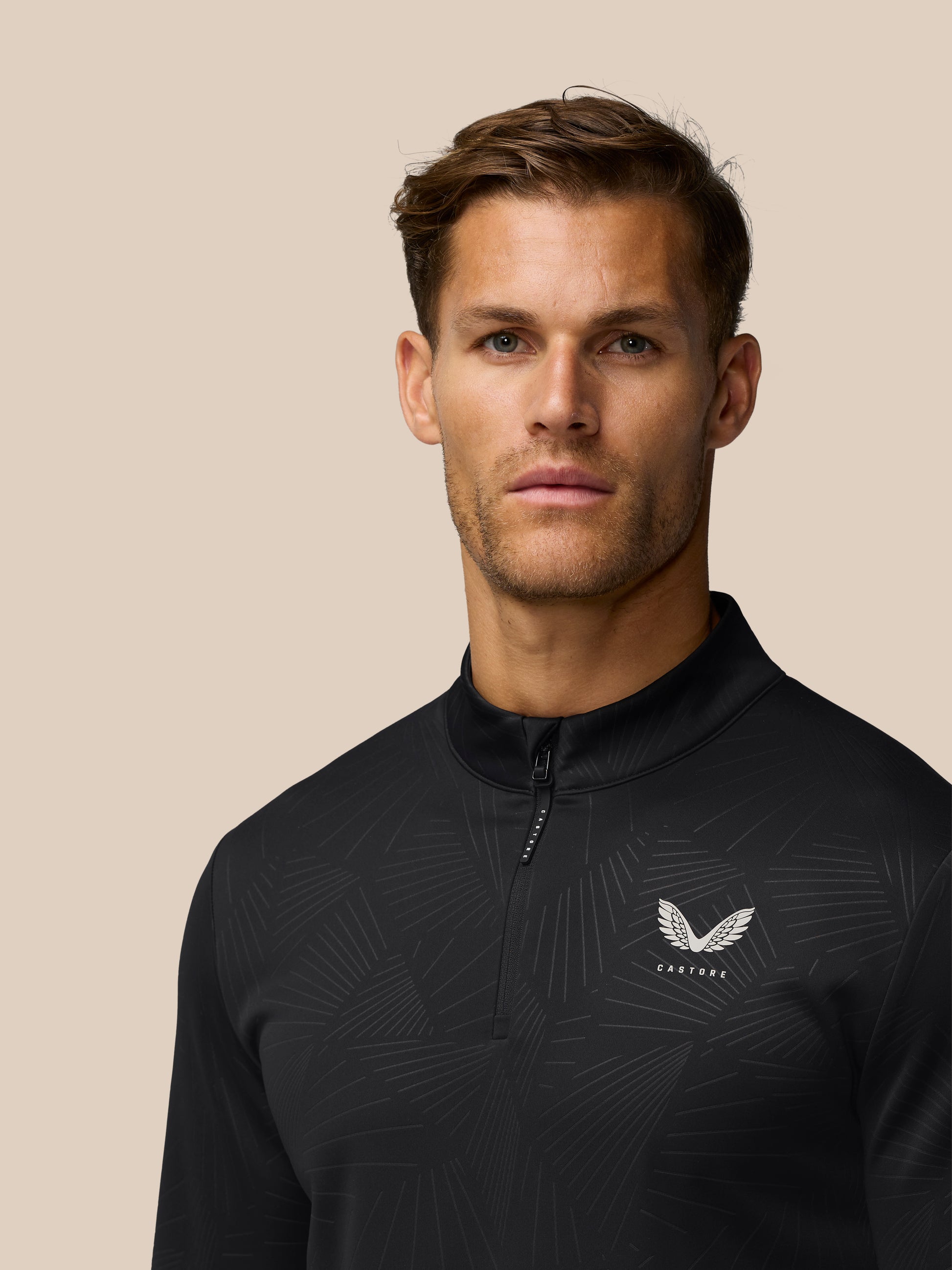 Male model wearing black Golf Club Classic quarter-zip top with a subtle line pattern and Castore wing logo on the chest.