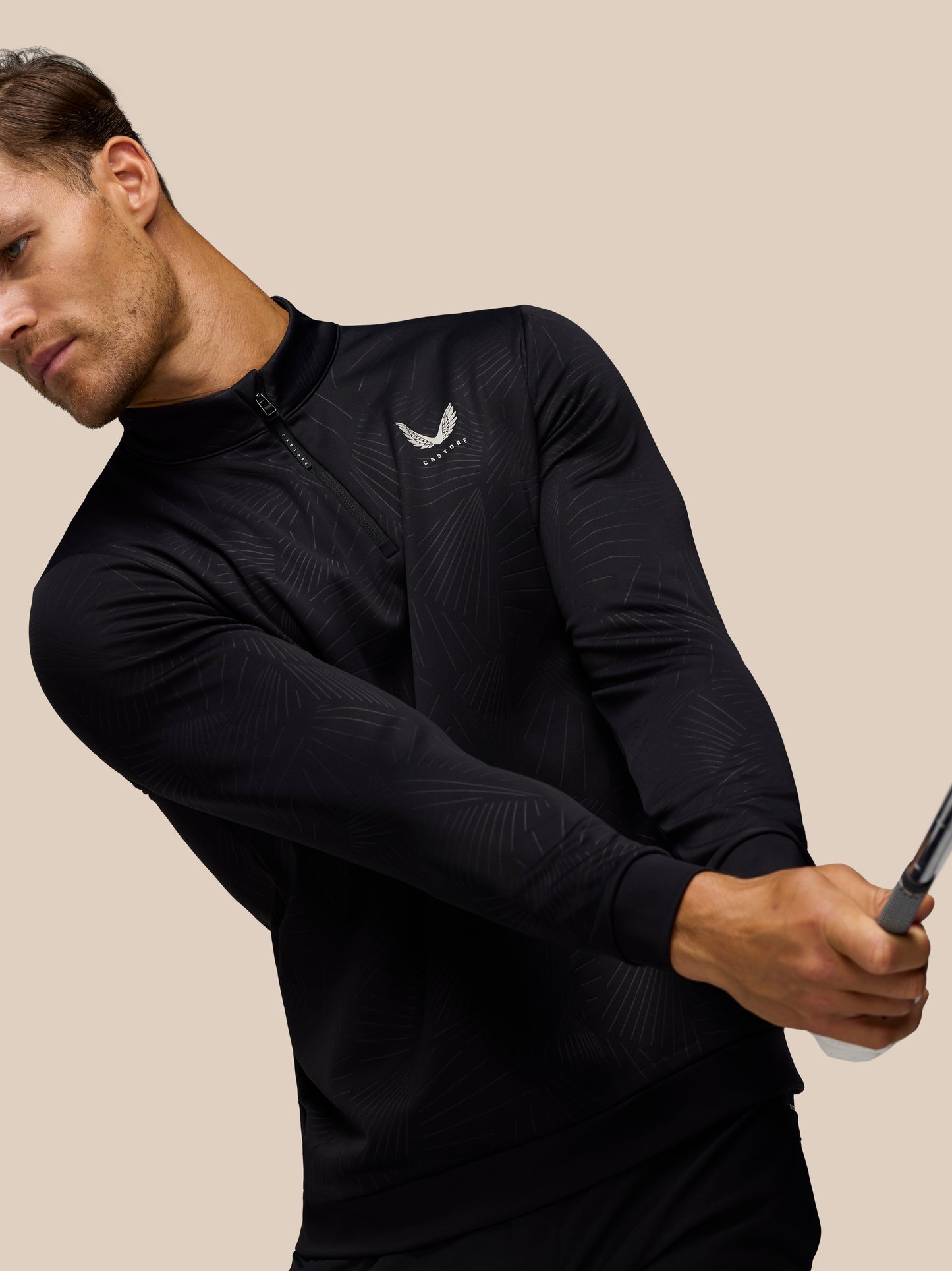 Close-up of male model wearing black Golf Club Classic 1/4 Zip Debossed Top with subtle print and Castore logo on chest.