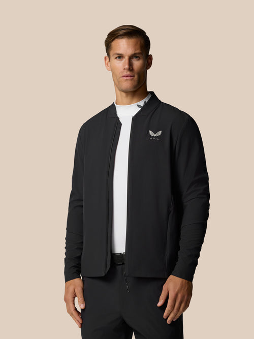 Front view of a man wearing a black Golf Pinnacle LVS Jacket with the Castore logo on the left chest