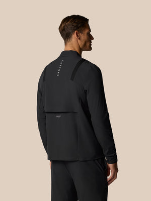 Back view of a man wearing a black Golf Pinnacle LVS Jacket with vertical Castore branding down the back and shoulder details