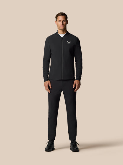 Three-quarter front view of a man in a black Golf Pinnacle LVS Jacket with a zip front and Castore logo on the left chest