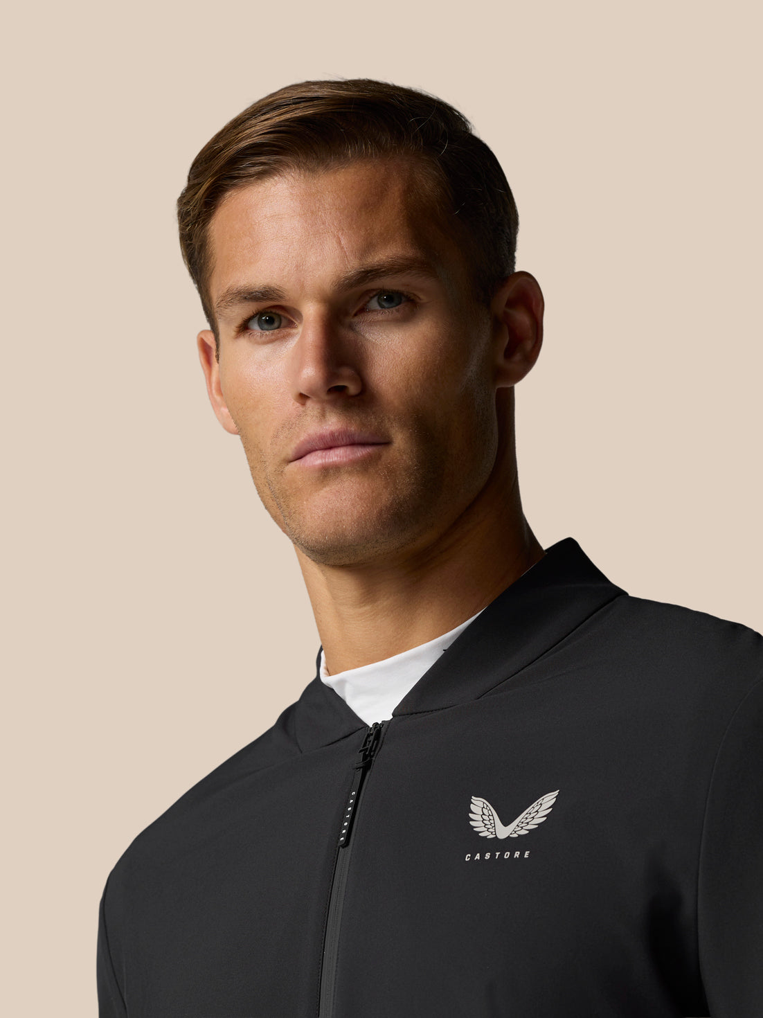 Close up of a man in a black Golf Pinnacle LVS jacket showing the front zip and left chest logo.