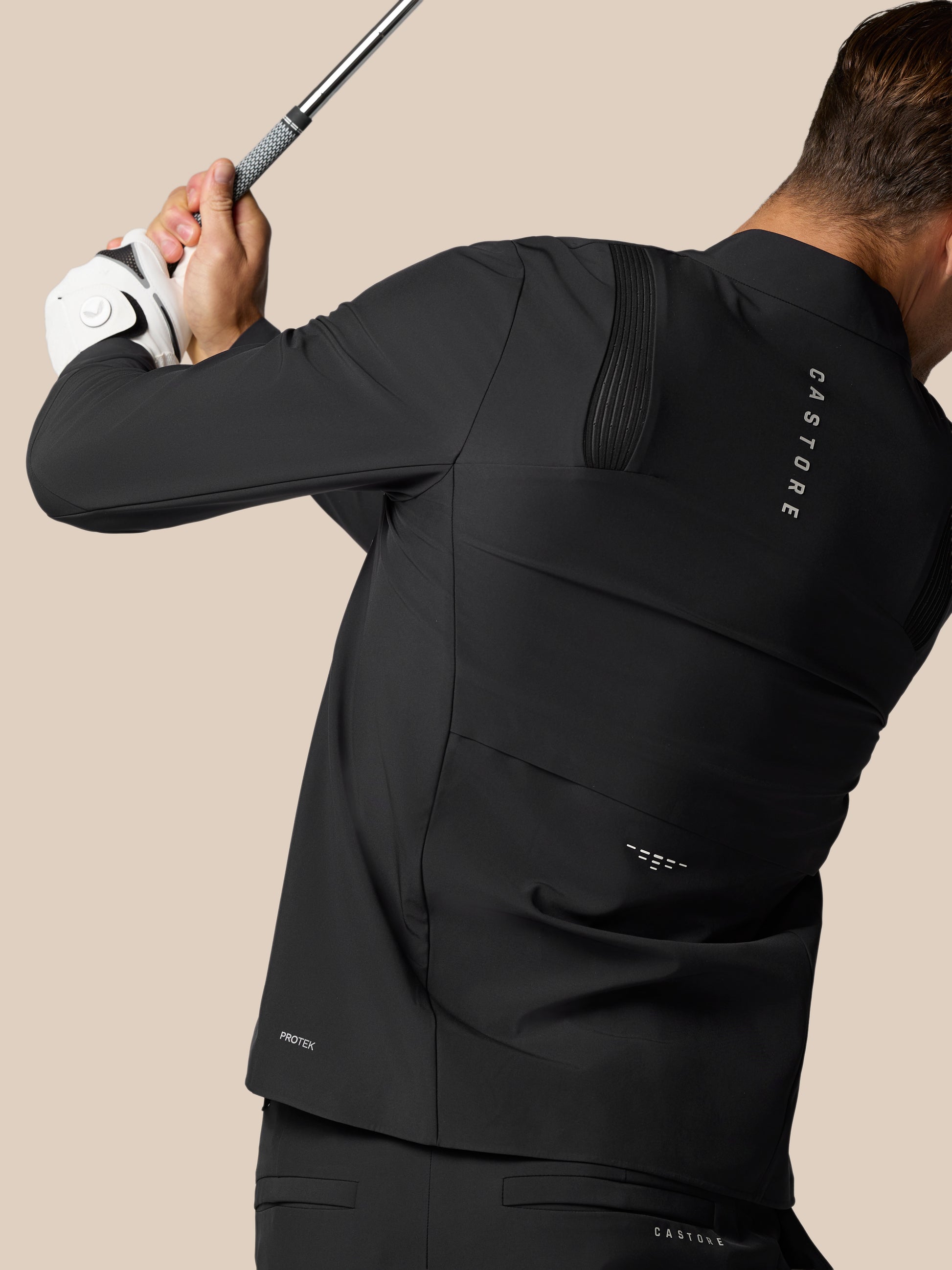 Back view of the black LVS jacket with a ribbed panel on the upper back and Protek branding near the hem.