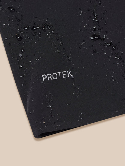 Close-up of black waterproof jacket fabric with water droplets and PROTEK branding.