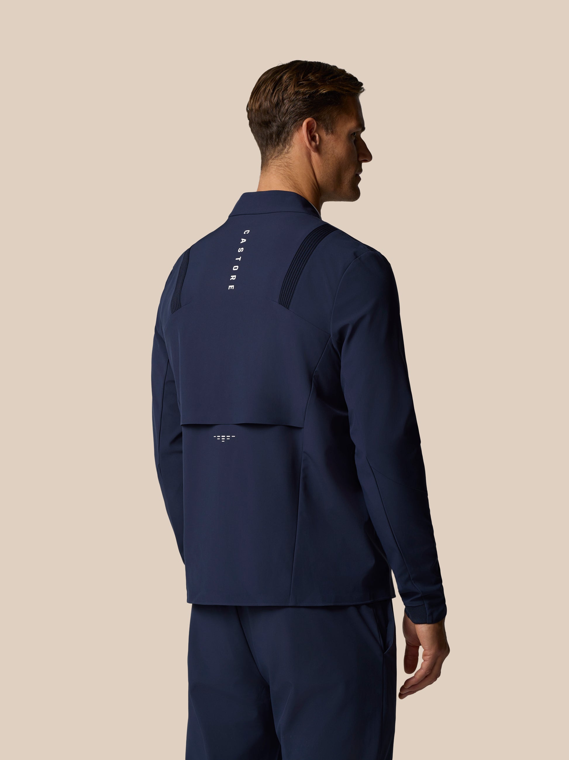 Back view of navy Golf Pinnacle LVS Jacket showing vertical Castore branding and shoulder ventilation panels