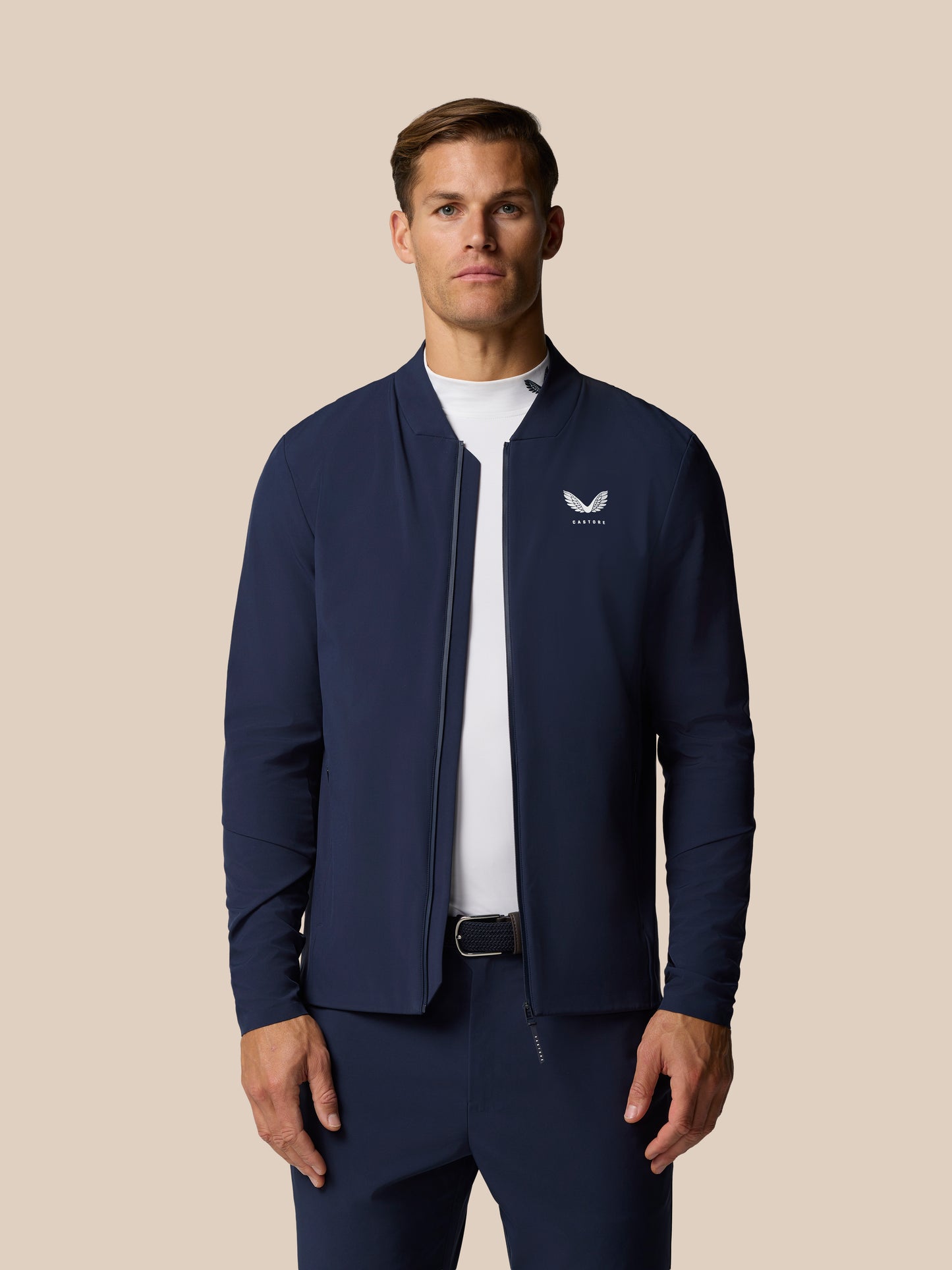 Male model wearing Golf Pinnacle LVS Jacket in Midnight Navy front view with Castore logo on chest.