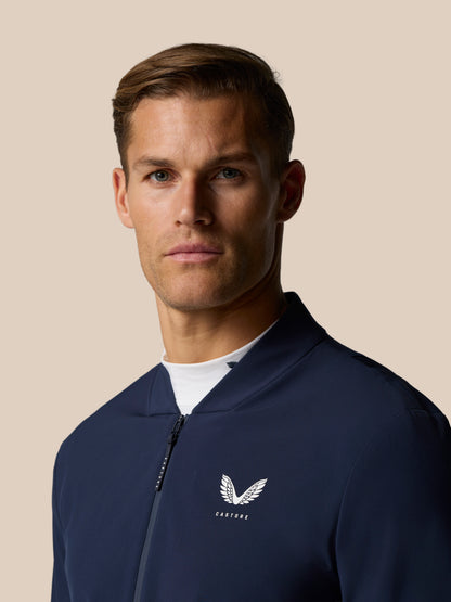 Close-up of navy Golf Pinnacle LVS Jacket showing front zipper and Castore logo on chest.