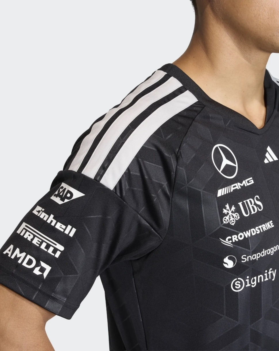 Close up of black Mercedes AMG Petronas driver T shirt shoulder with white triple stripes and sponsor logos on chest