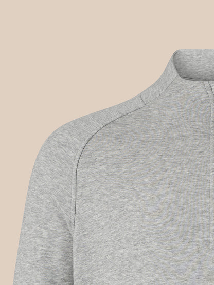 Close-up of a light gray heathered quarter-zip pullover sweater showing the shoulder seam and collar, set against a solid beige background.