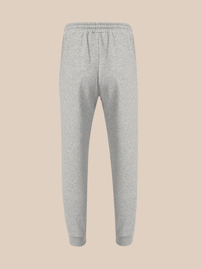 Light gray heather sweatpants with an elastic waistband and ribbed ankle cuffs, shown against a solid beige background.