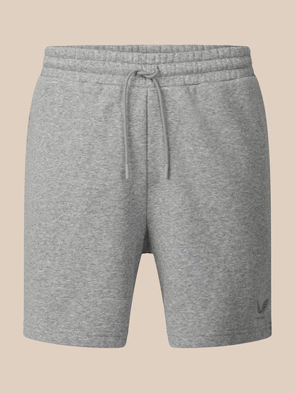 A pair of heather gray sweat shorts with an elastic drawstring waistband, shown against a solid beige background.