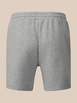 A pair of heather gray sweat shorts with an elastic waistband, shown from the back on a solid beige background.