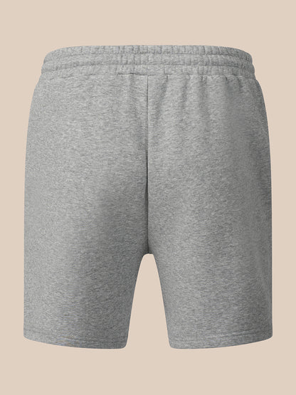 A pair of heather gray sweat shorts with an elastic waistband, shown from the back on a solid beige background.