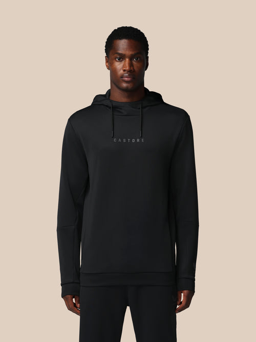 Man wearing a black hoodie with 'CASTORE' branding on a beige background