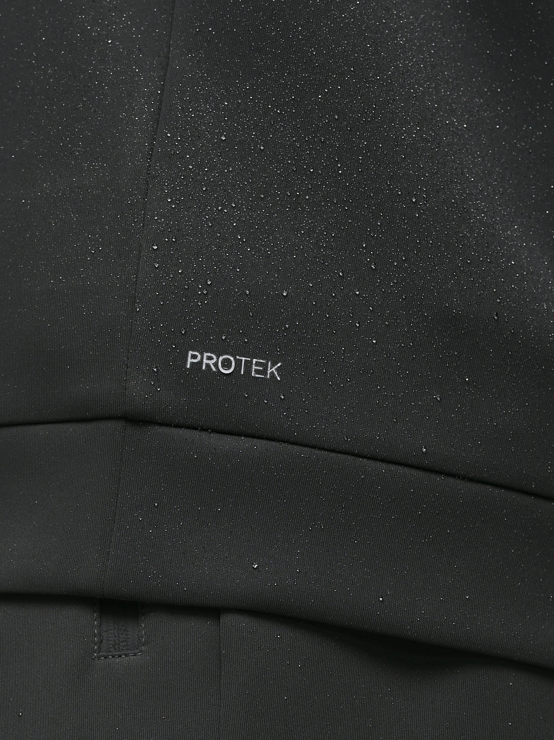 Close up of black ProTek fabric with water droplets and branding on the chest area