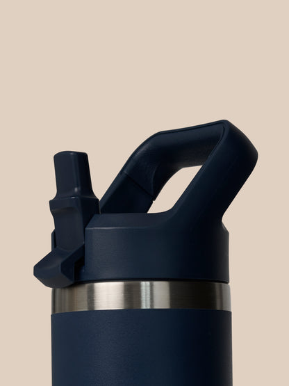 Close up of the YETI Rambler 532 ml lid and handle assembly on a dark blue bottle against beige backdrop