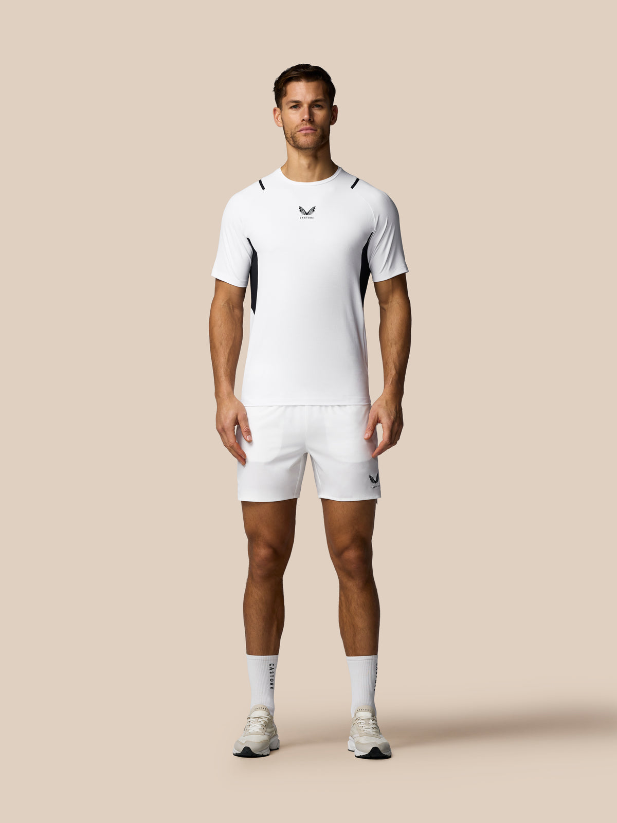 Man wearing a white athletic outfit with a logo on a beige background