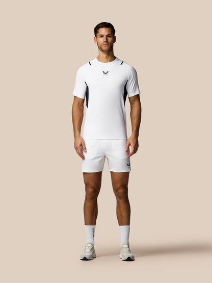 Man wearing a white athletic outfit with a logo on a beige background
