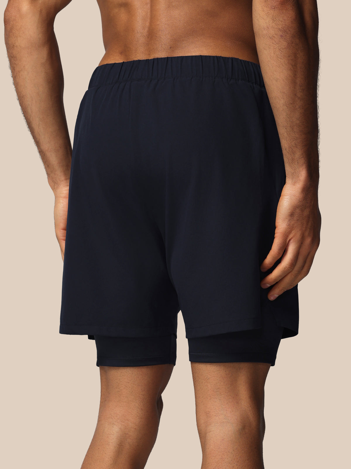 Person wearing navy blue shorts on a beige background