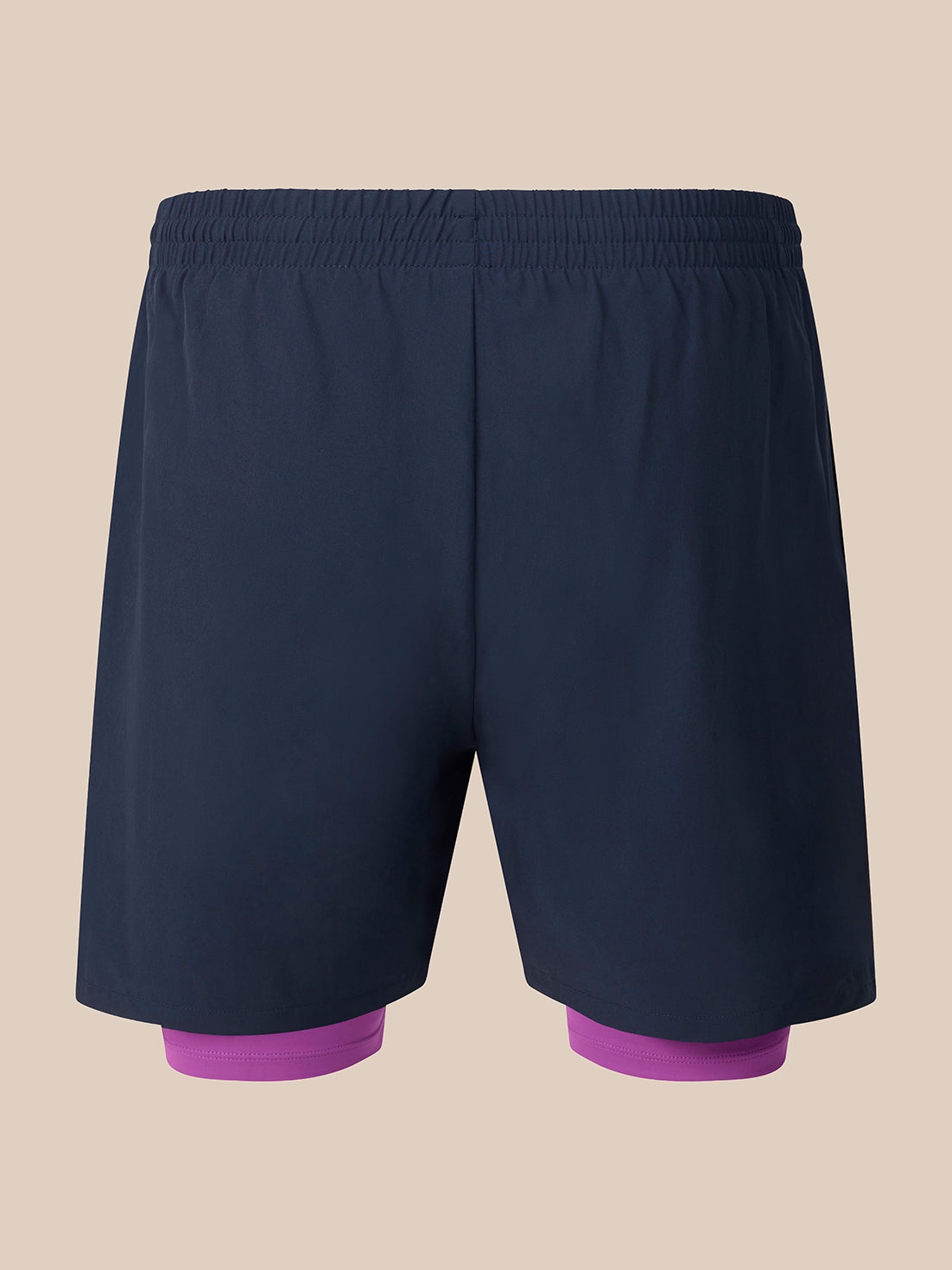Dark navy athletic shorts with a built-in purple compression liner visible at the legs, shown against a solid beige background.