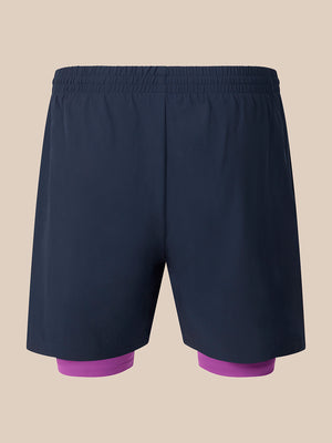 Dark navy athletic shorts with a built-in purple compression liner visible at the legs, shown against a solid beige background.