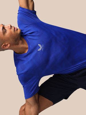 Person wearing a blue athletic shirt with a logo on a beige background