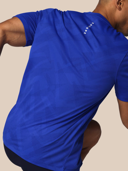 Person wearing a blue athletic shirt with a brand logo on a beige background