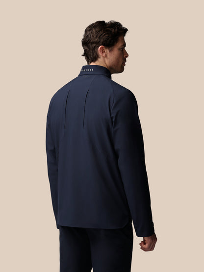 Back view of a man in navy Castore jacket showing vertical back seams and logo on the collar