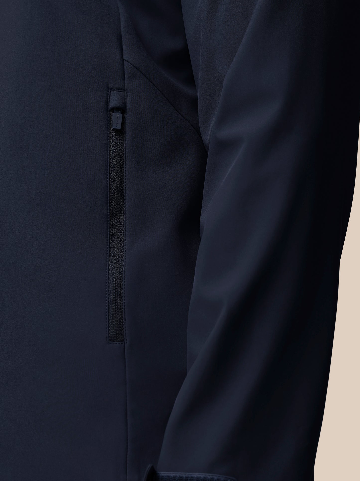 Detail of navy jacket zipper with Castore pull on dark fabric