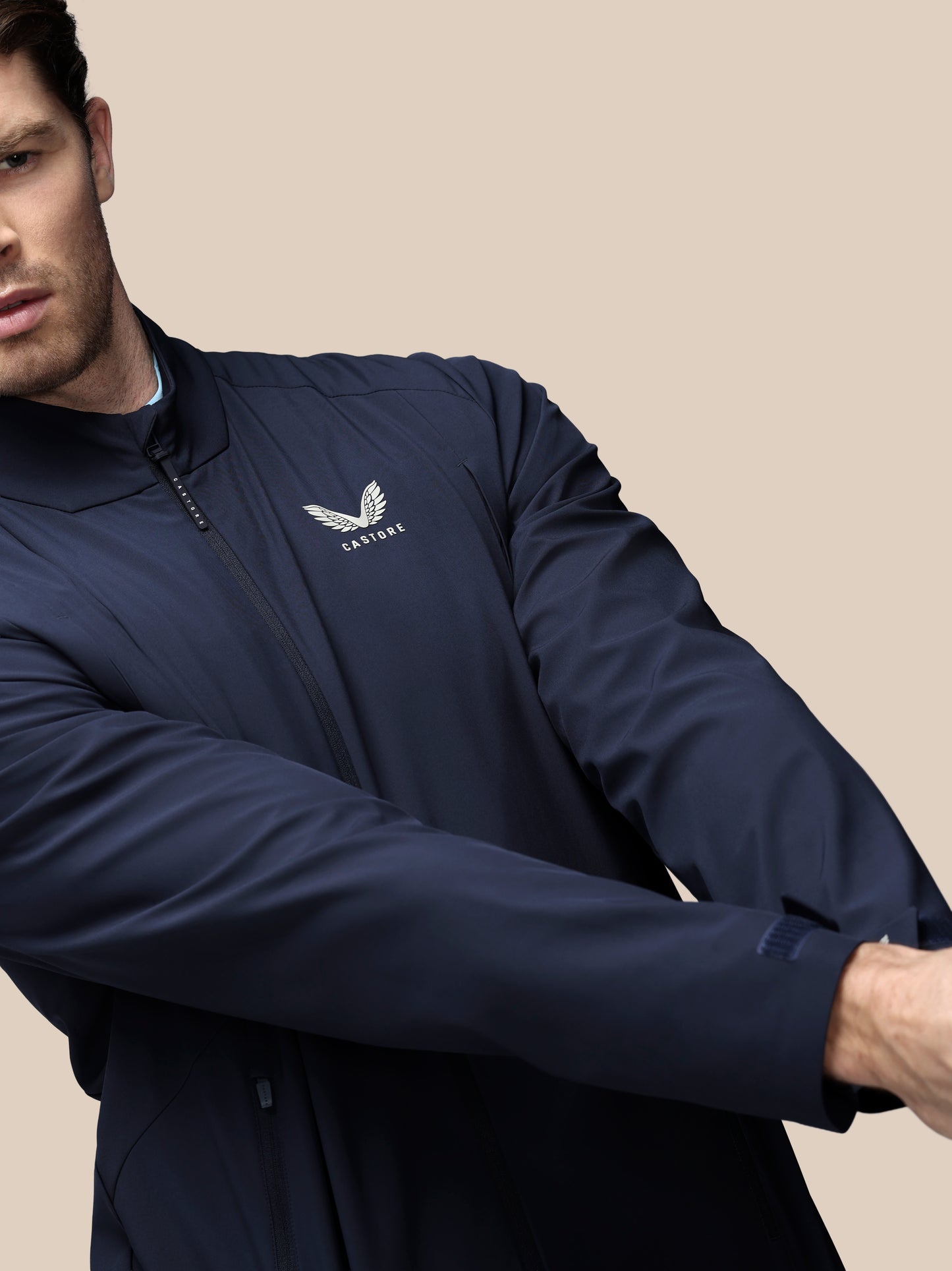 Profile view of a man wearing navy LVS woven jacket with Castore wordmark at the back neck