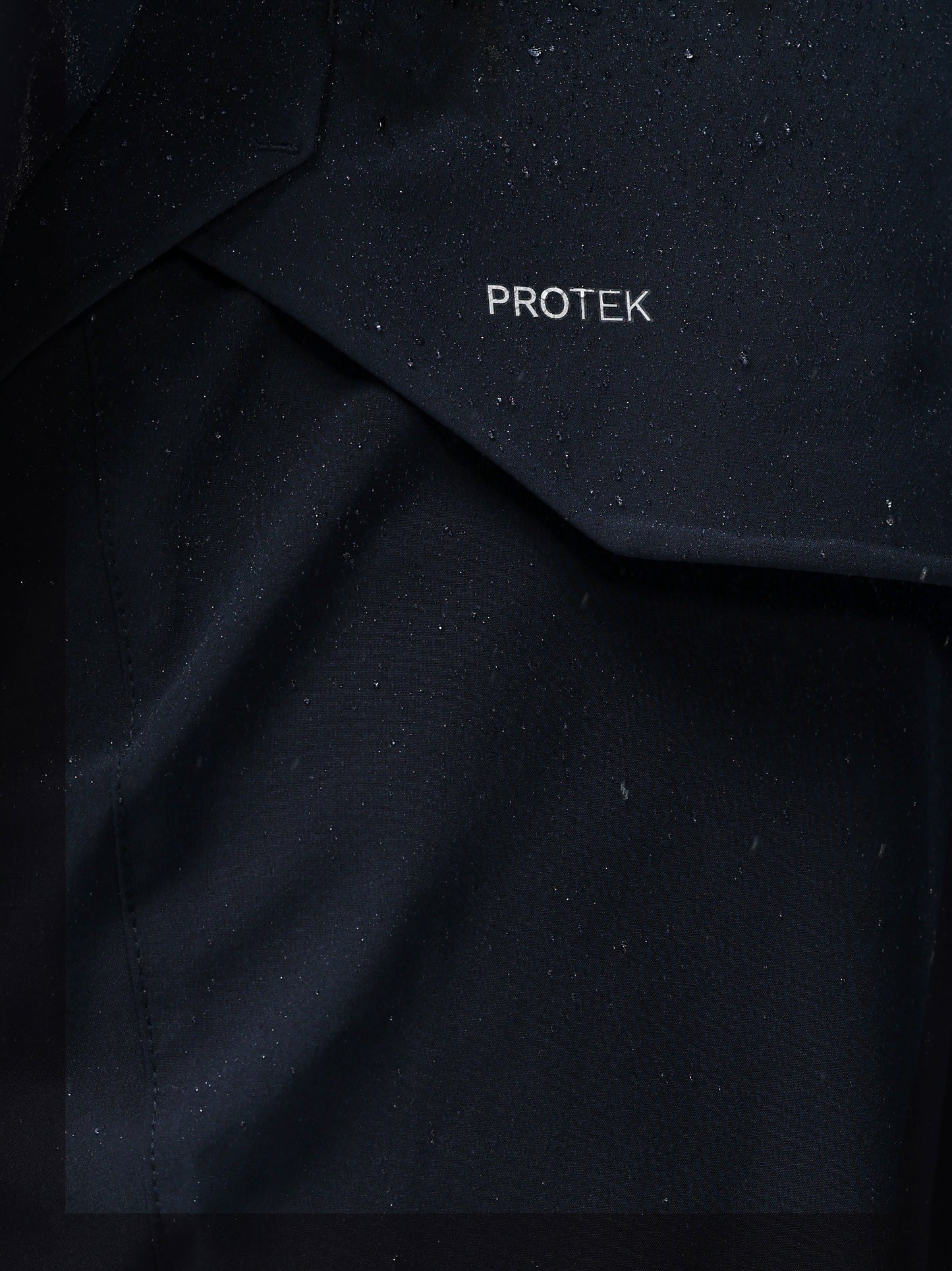 Close-up of navy jacket fabric with PROTEK branding