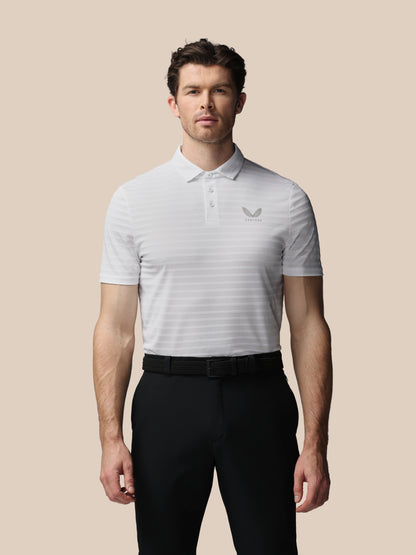 Man wearing a white striped polo shirt with a logo on a beige background