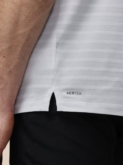 Close-up of a person wearing a white shirt with 'AERTEK' branding, focusing on the collar area.