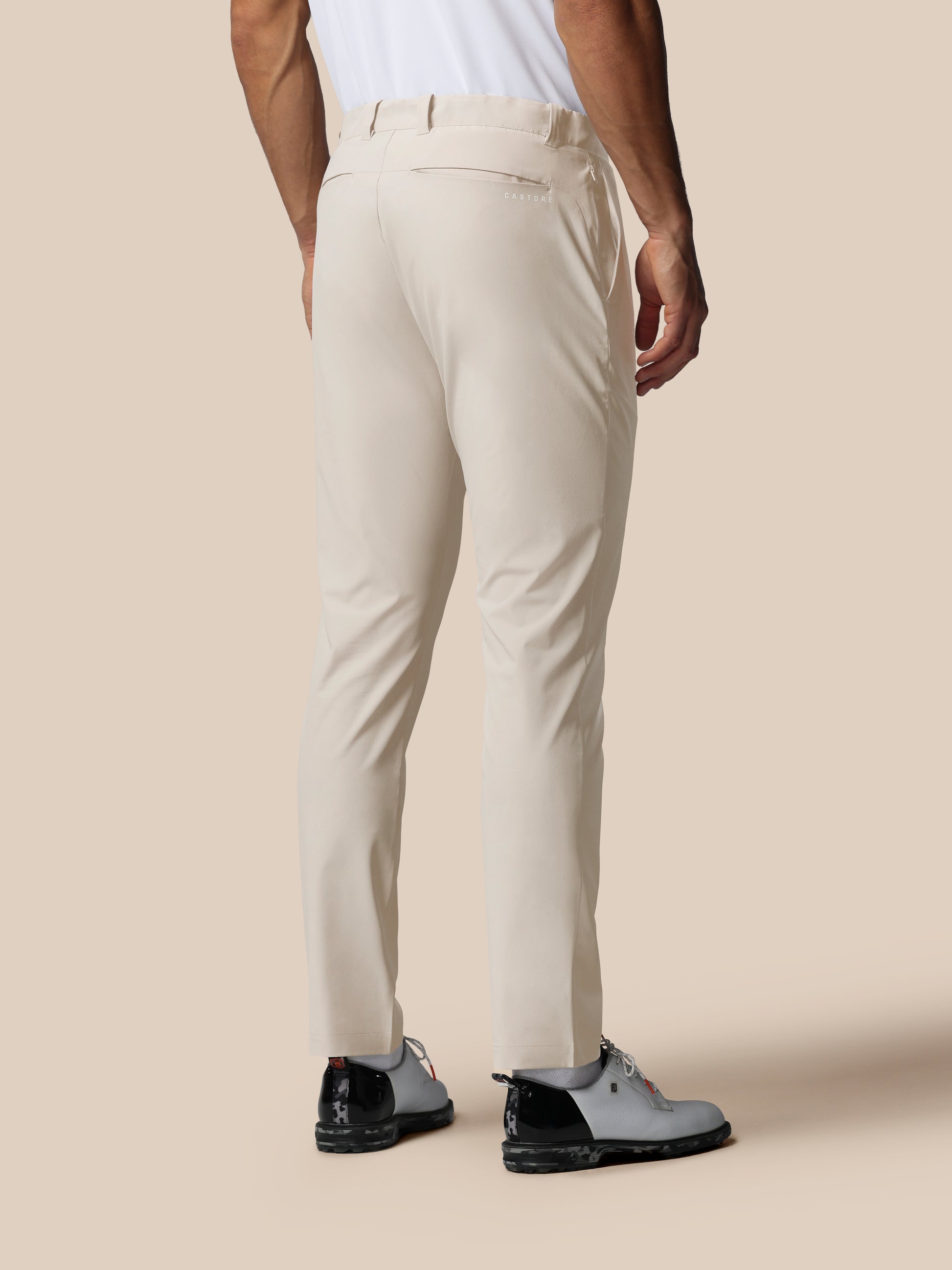 Back view of a model in cream golf trousers showing rear pocket and Castore logo