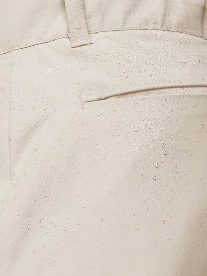 Close-up of cream golf trouser fabric with water droplets and ProTek branding.